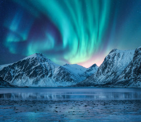 Wall Mural - aurora borealis over the snowy mountains, coast of the lake and reflection in water. northern lights