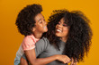 © Brastock Images - Portrait of young African American mother with toddler son. Yellow background. Brazilian family.