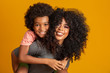 © Brastock Images - Portrait of young African American mother with toddler son. Yellow background. Brazilian family.