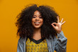 © Brastock Images - Beautiful curly-haired girl using her hands ok sign. Yellow background.
