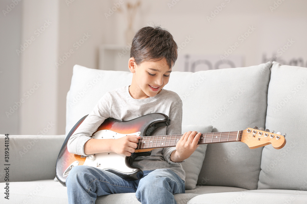 Little boy playing guitar at home