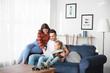 © Pixel-Shot - Happy young family reading book while sitting on sofa at home