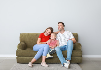 Wall Mural - Happy young family sitting on sofa near light wall