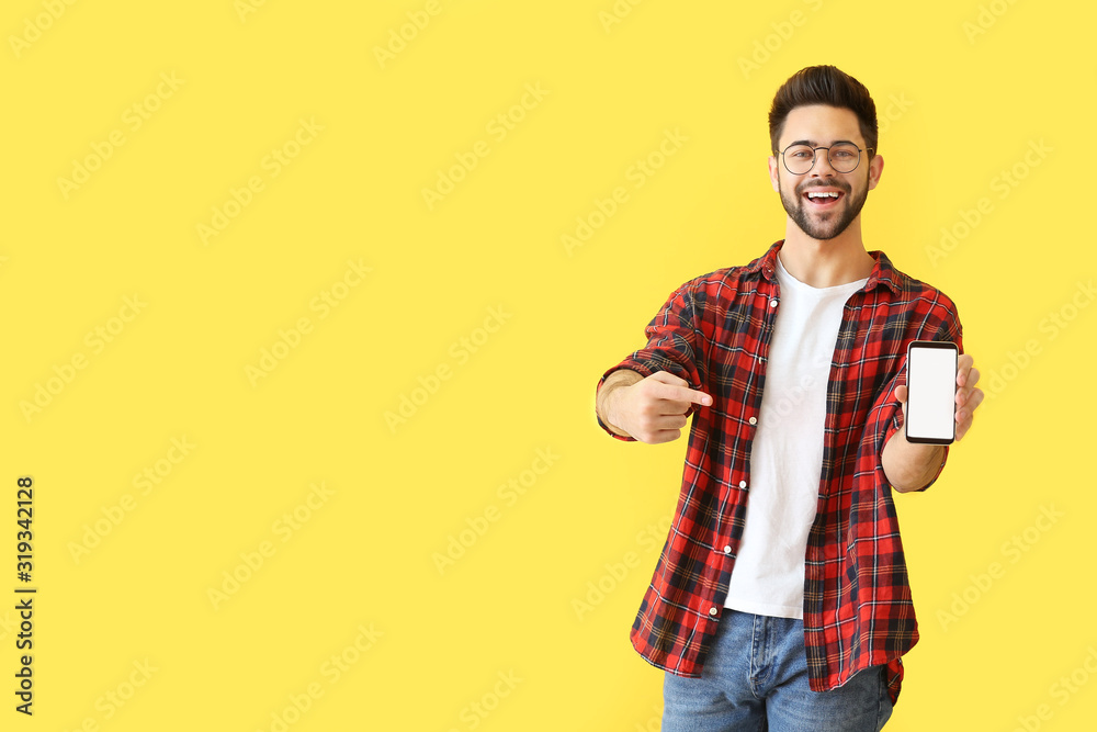 Happy young man with mobile phone on color background - obrazy, fototapety, plakaty 