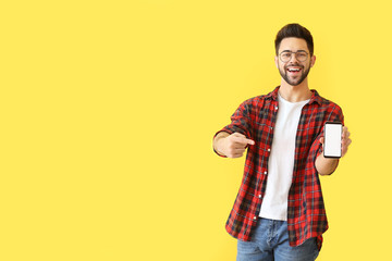 Wall Mural - Happy young man with mobile phone on color background