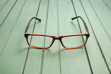 Stylish eyeglasses on wooden table