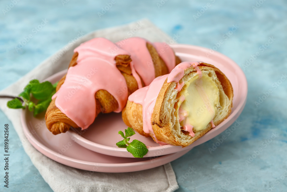 Plates with tasty sweet croissants on color background
