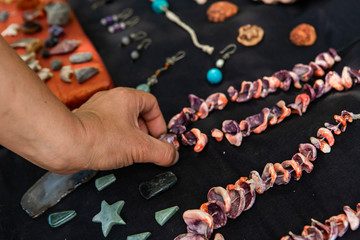 Wall Mural - Close up of man's hand choosing a necklace from the stand of a vendor. Local farmer's market hand made jewelery shop with jewels on black velvet cloth