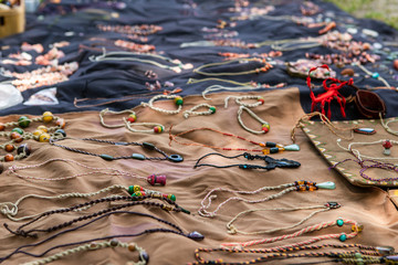 Colored necklaces and other hand made jewels neatly exposed on beige and blue cloths. Craft shop at the local farmer's market. Selective focus shot of 