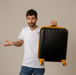 © SB Arts Media - Stylish handsome man showing suitcase. Advertising storage space for travelers and tourism image.