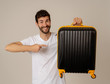 © SB Arts Media - Stylish handsome man showing suitcase. Advertising storage space for travelers and tourism image.