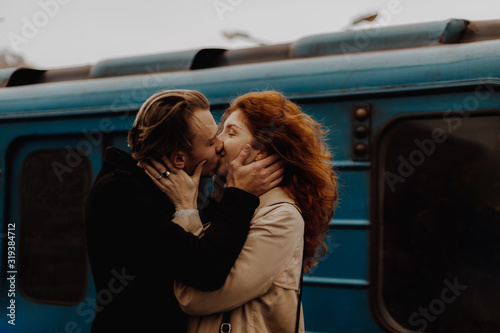 Young couple in love kissing against train in train station. Tableau sur Toile