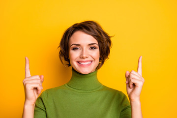 Closeup photo of beautiful lady indicating fingers up empty space advising buyers customers low prices wear casual warm green turtleneck isolated yellow color background