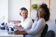 © Mangostar - Cheerful colleagues laughing during work. Happy office workers sitting at table with VR headsets and laptops. Technology concept