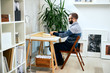 © Tijana - Attractive freelance male sitting in modern office and typing on notebook.
