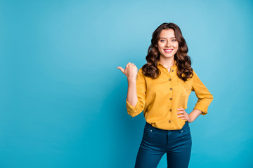 Wall Mural - Photo of lovely business manager lady indicating thumb finger empty space advising new product low price wear yellow shirt pants isolated blue color background