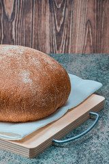 Poster - round loaf of wheat bread with a baked shiny crust on the kitchen table