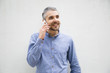 © Mangostar - Smiling young man talking on phone. Cheerful guy holding smartphone near ear and looking aside. Technology and communication concept