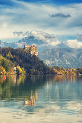 Wall Mural - Famous alpine Bled lake (Blejsko jezero) in Slovenia, amazing autumn landscape. Aerial view of the lake, Bled castle, mountains and blue sky with clouds, outdoor travel vertical background