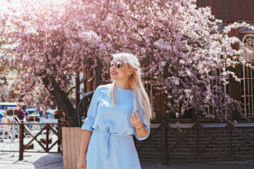 Beautiful model in blue dress by spring blooming tree