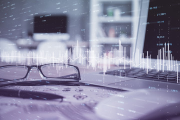 Financial chart hologram with glasses on the table background. Concept of business. Double exposure.