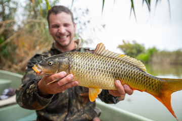 Wall Mural - Young happy angler holds the big Carp fish