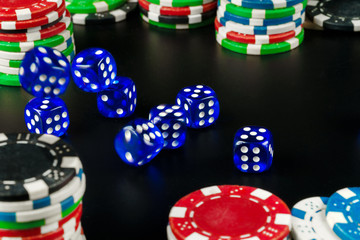 Dice and chips on black table close up