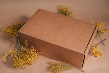Closed Carton Box With Flowers And Plants Decoration On The Brown Background