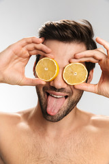 Wall Mural - Photo of cheerful half-naked man laughing and making fun with lemon