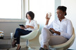 © Mangostar - Businesswomen drinking coffee and using digital tablets. Multiethnic female colleagues sitting in chairs and using tablet computers in office during coffee break. Technology concept