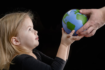 Wall Mural - Mother gives the planet into the hands of a child. Isolated on dark background