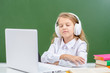 © Ermolaev Alexandr - A young female student sitting in the classroom, using laptop and headphones, listening to the music