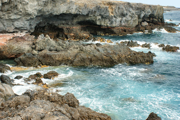 east coast of tenerife. rocky grotto and azure sea. waves constantly hitting the rocky shore.