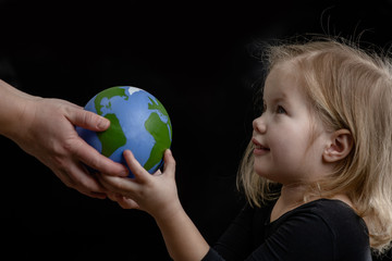 Wall Mural - Mother gives the planet into the hands of a child. Isolated on dark background