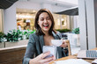 © BullRun - Asian laughing young woman with coffee cup and smartphone