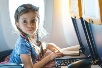 curious girl with book at airplane