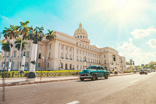 Photo vintage American retro car rides on an asphalt road in front of the Capitol in old Havana