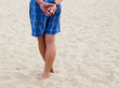 © svetlana8art - A barefoot man stands in the sand on the seashore.