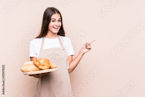 Fotomural Young caucasian baker woman isolated smiling and pointing aside, showing something at blank space
