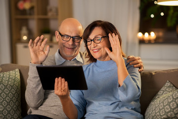 Sticker - technology, old age and people concept - happy smiling senior couple with tablet pc computer having video call at home in evening