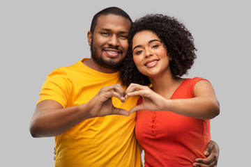 Wall Mural - love, valentines day and people concept - happy african american couple making hand heart gesture over grey background