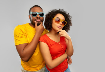 love, relationships and summer concept - african american couple in sunglasses thinking over grey background