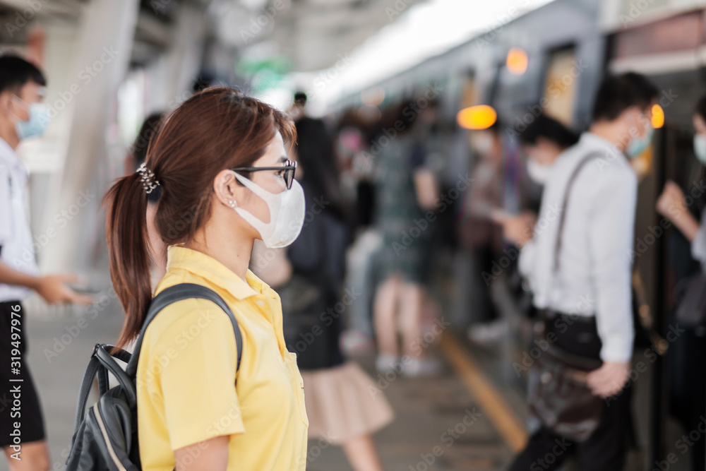 young Asian woman wearing protection mask against Novel coronavirus (2019-nCoV) or Wuhan coronavirus at public train station,is a contagious virus that causes respiratory infection.Healthcare concept - obrazy, fototapety, plakaty 