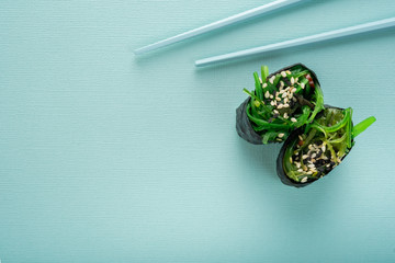 Two Chuka seaweed Sushi with chopsticks on a blue background, top view