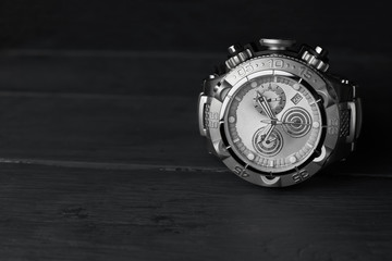 Stainless steel wristwatch on a dark wooden background.