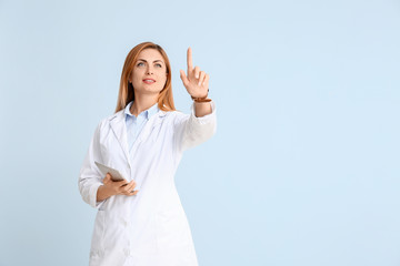 Poster - Portrait of female doctor with tablet computer showing something on color background