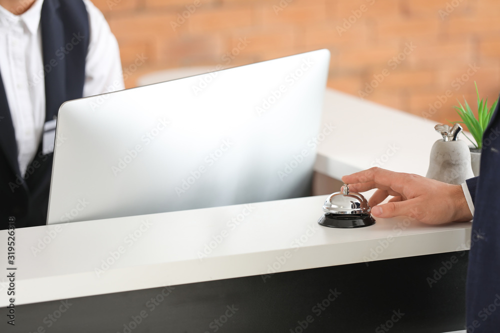 Man ringing service bell on reception desk in hotel