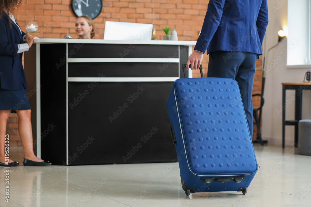 Young man going to reception desk for booking a room in hotel