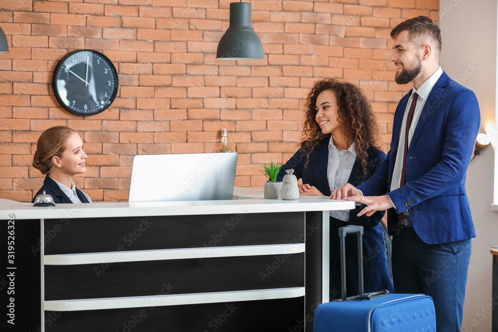 Young female receptionist working with guests in hotel