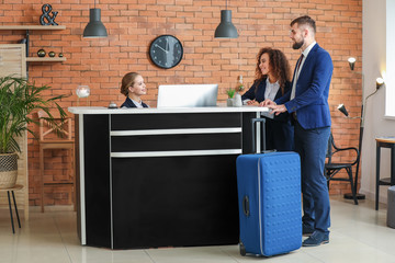 Poster - Young female receptionist working with guests in hotel